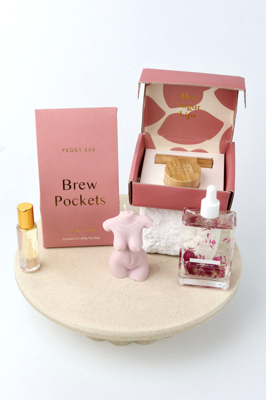 The 'Glow' Gift box. This bath and body hamper includes Bath brew pockets and a silk ip care kit by Peggy Sue. A crystal perfume roller and Spring of seed body oil by Bopo Women and a handmade soy wax lady figure candle.