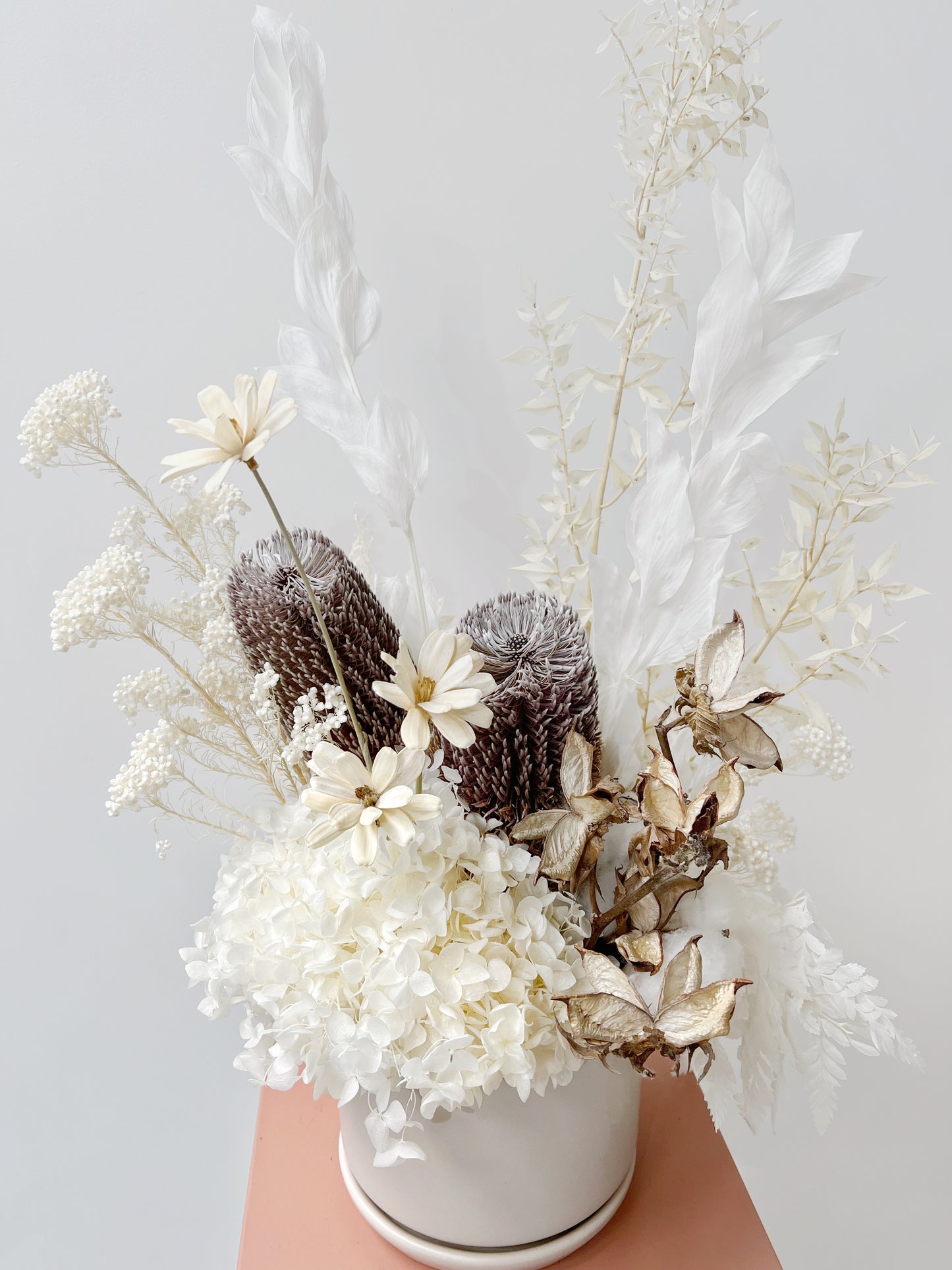 An everlasting flower arrangement in whites and native focals.