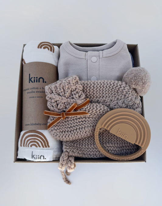 Baby hamper in hazelnut tones. Including organic cotton swaddle and teeth by Kiin and merino wool beanie and bootie set and a growsuit from Snuggle Hunny Kids. Presented in gift box.