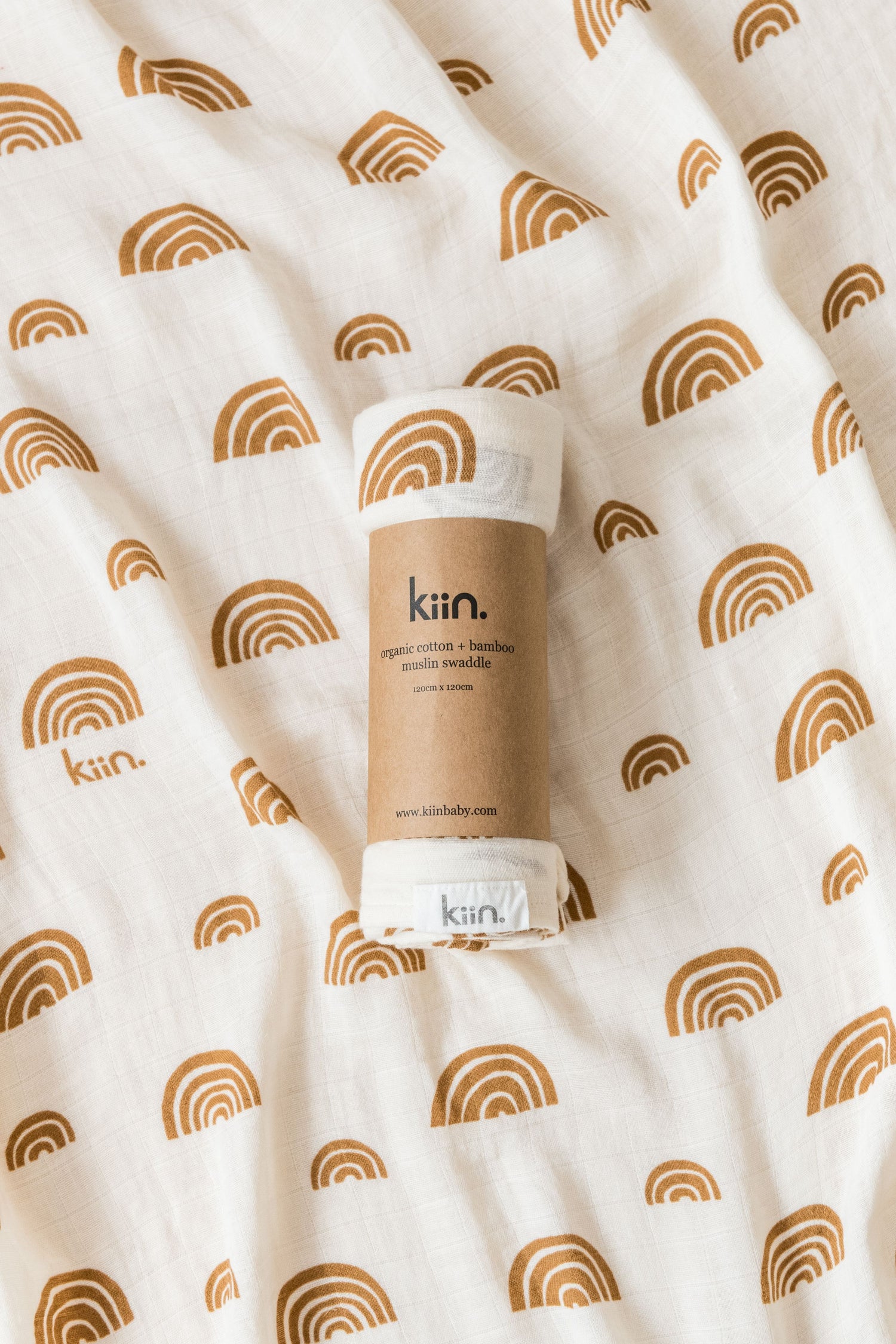 Organic swaddle in oat, with soft brown rainbows by Kiin Baby.